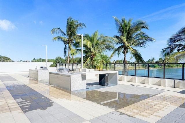 exterior space featuring exterior kitchen, a water view, and a patio area