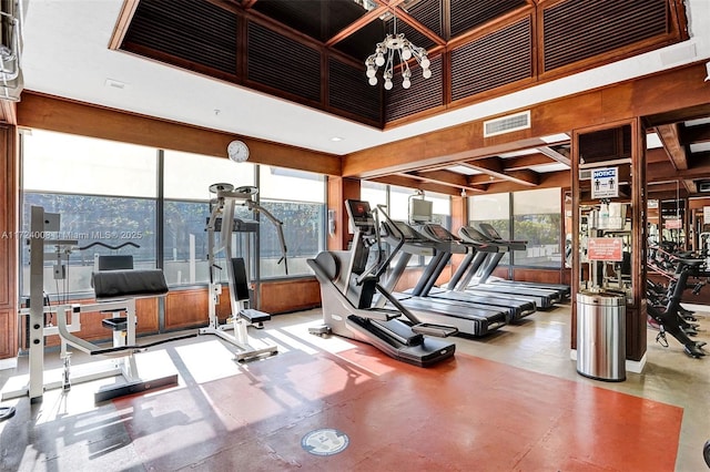 gym with a high ceiling and a notable chandelier