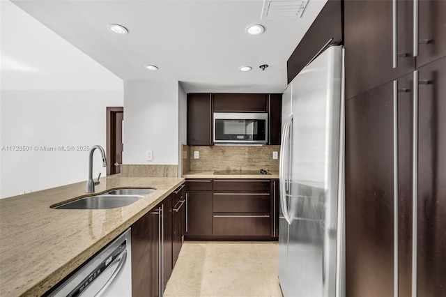 kitchen with sink, light tile patterned floors, stainless steel appliances, light stone counters, and decorative backsplash