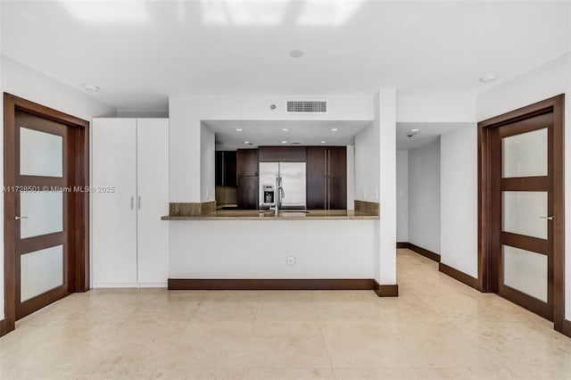 kitchen with dark brown cabinetry, sink, kitchen peninsula, and stainless steel built in refrigerator