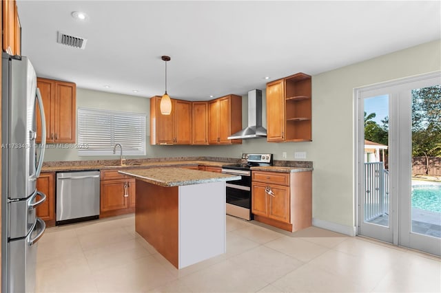 kitchen featuring sink, hanging light fixtures, a center island, stainless steel appliances, and wall chimney exhaust hood