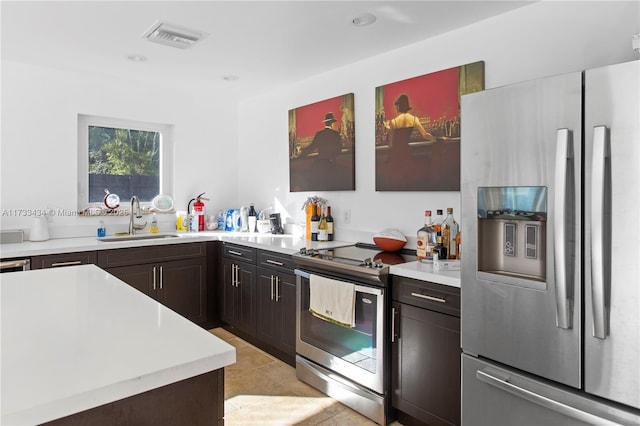 kitchen featuring sink, light tile patterned floors, dark brown cabinets, and appliances with stainless steel finishes