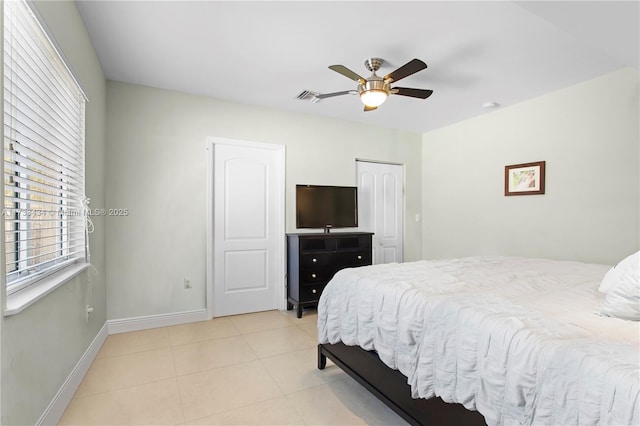 tiled bedroom with ceiling fan and a closet