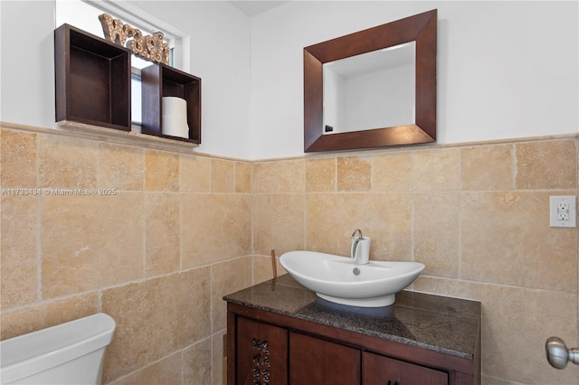 bathroom with tile walls, vanity, and toilet