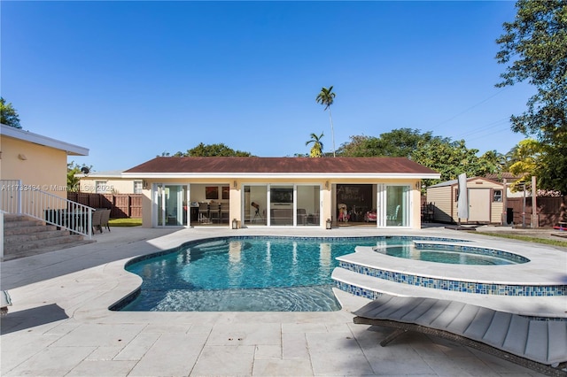 view of pool featuring a shed, a patio, and an in ground hot tub