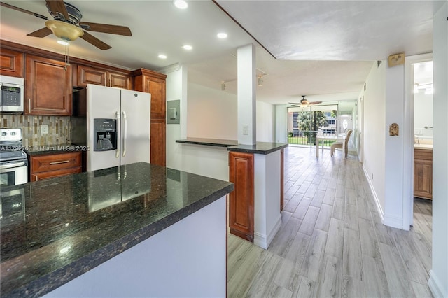 kitchen featuring dark stone countertops, backsplash, stainless steel appliances, and light hardwood / wood-style floors