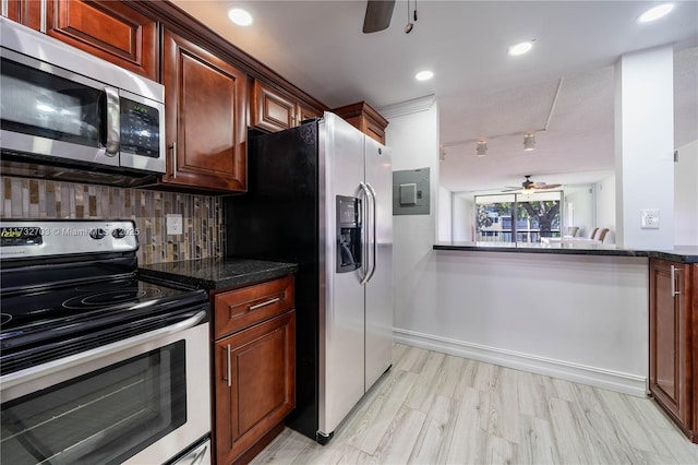 kitchen featuring rail lighting, ceiling fan, dark stone countertops, stainless steel appliances, and decorative backsplash