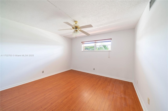 empty room featuring ceiling fan, hardwood / wood-style floors, and a textured ceiling