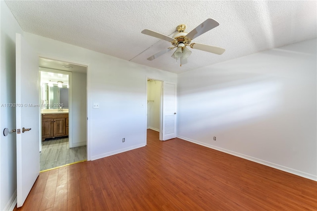 unfurnished bedroom with hardwood / wood-style flooring, ceiling fan, connected bathroom, and a textured ceiling