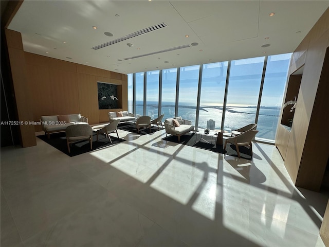 living room with a wall of windows, a healthy amount of sunlight, and a water view