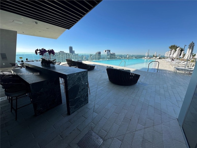 view of patio with a water view, exterior bar, and a community pool