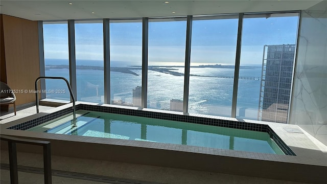 view of swimming pool with an indoor in ground hot tub and a water view