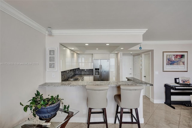 kitchen featuring a breakfast bar, stainless steel fridge with ice dispenser, white cabinetry, sink, and kitchen peninsula