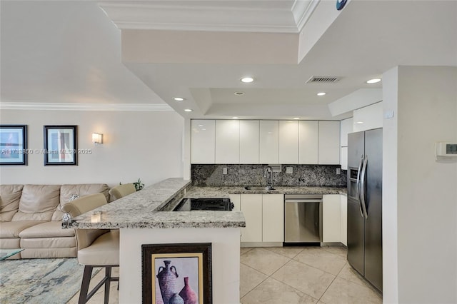 kitchen featuring stainless steel appliances, white cabinetry, a kitchen bar, and kitchen peninsula