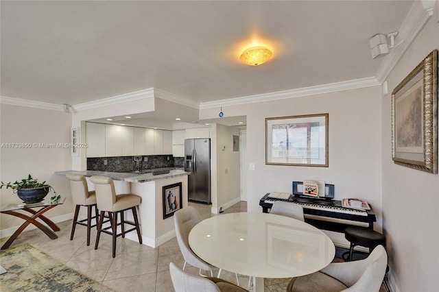 dining room with baseboards, ornamental molding, and light tile patterned flooring