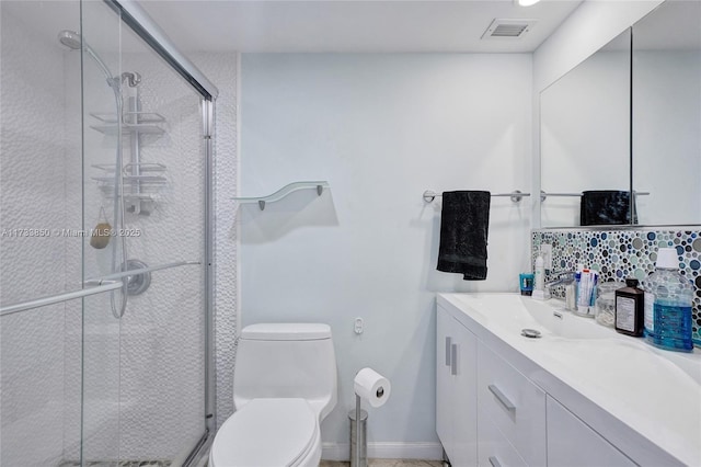 bathroom with vanity, toilet, a shower with door, and backsplash