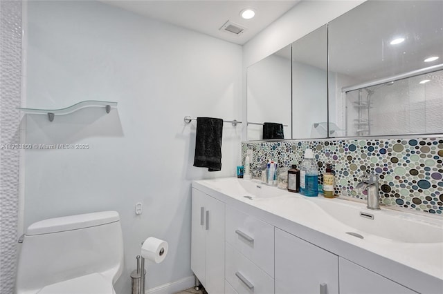 bathroom with vanity, backsplash, a shower with door, and toilet