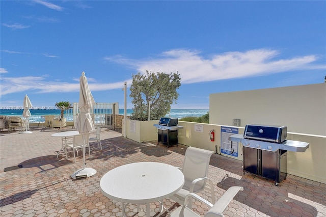 view of patio featuring a grill, a beach view, and a water view