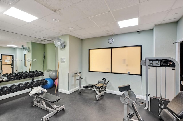 gym featuring baseboards and a drop ceiling