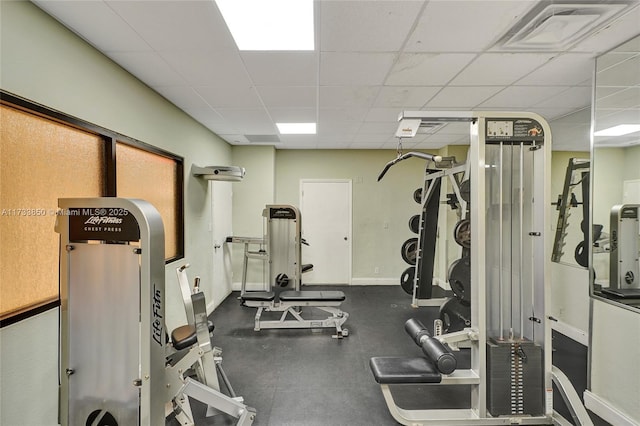 gym with baseboards, a drop ceiling, and visible vents