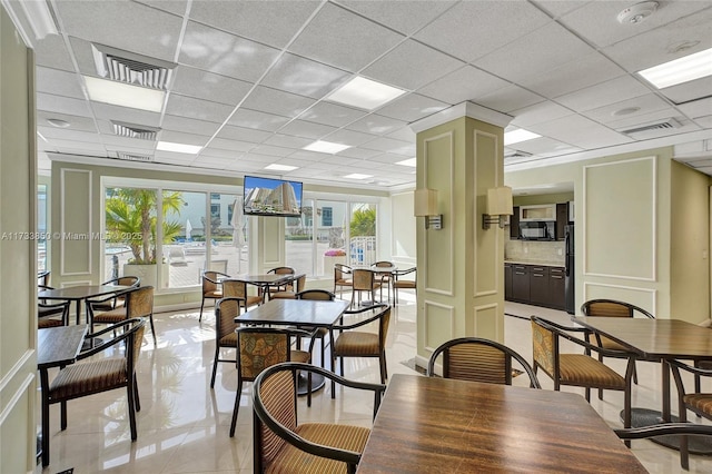 dining space with light tile patterned flooring and a paneled ceiling