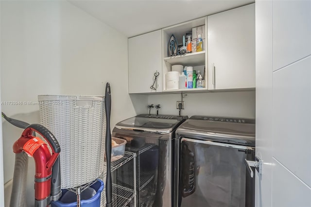 clothes washing area featuring washer and dryer and cabinets