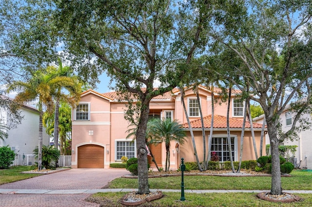 mediterranean / spanish-style house with a garage and a front lawn