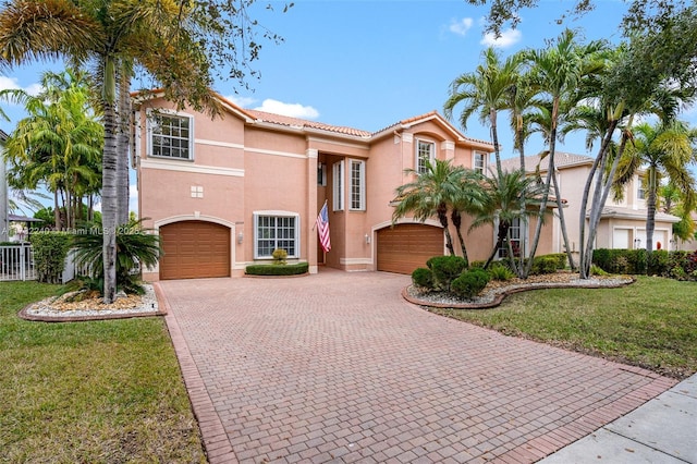 mediterranean / spanish home featuring a garage and a front lawn