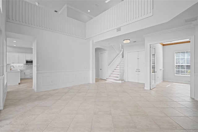 tiled spare room with sink, crown molding, and a high ceiling