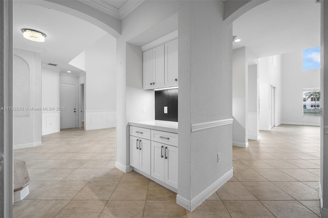 corridor featuring light tile patterned floors and ornamental molding