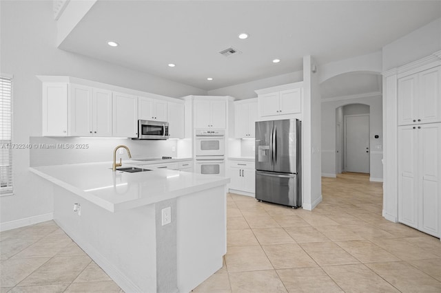 kitchen featuring sink, white cabinets, light tile patterned floors, kitchen peninsula, and stainless steel appliances