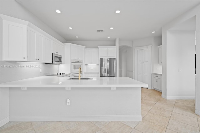 kitchen with white cabinetry, stainless steel appliances, light tile patterned flooring, and sink