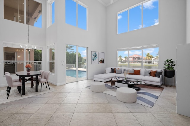 living room with an inviting chandelier, a towering ceiling, light tile patterned floors, and a wealth of natural light