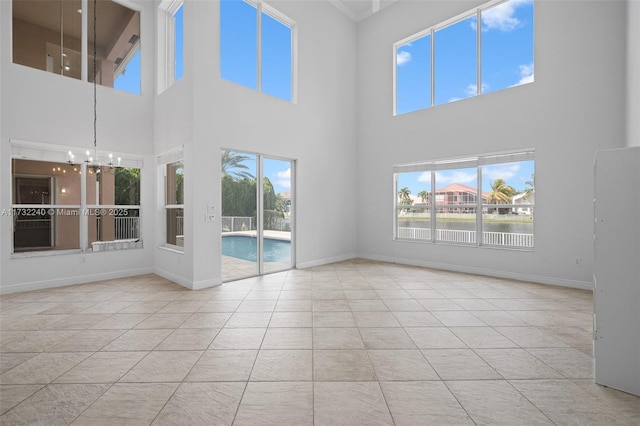 interior space featuring a high ceiling, a water view, and an inviting chandelier