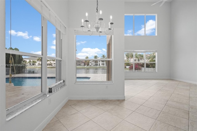 unfurnished sunroom with a water view and a chandelier