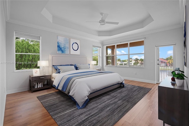 bedroom featuring multiple windows, access to outside, a raised ceiling, and ceiling fan