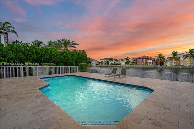 pool at dusk featuring a patio area and a water view