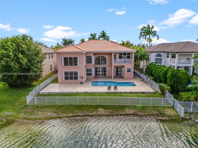 rear view of house with a fenced in pool, a patio area, a balcony, and a water view