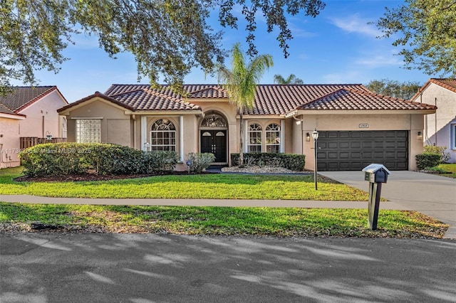 mediterranean / spanish home featuring a garage and a front lawn