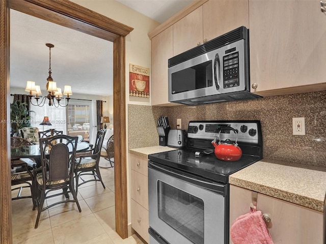 kitchen with appliances with stainless steel finishes, pendant lighting, backsplash, light tile patterned floors, and light brown cabinets