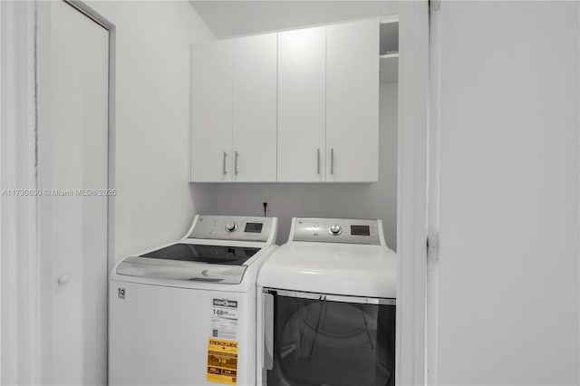 clothes washing area featuring cabinets and washing machine and dryer