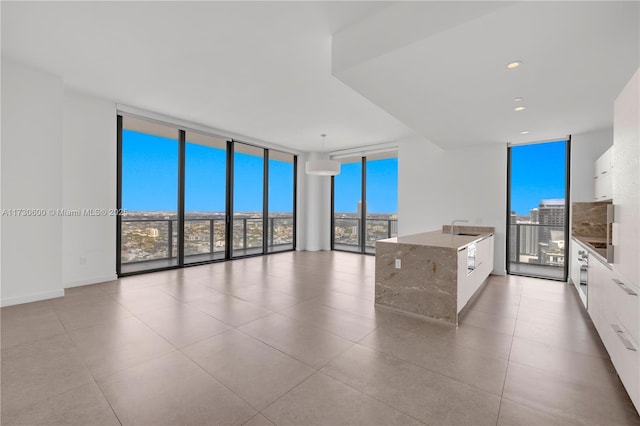 interior space featuring sink, floor to ceiling windows, white cabinets, stone countertops, and decorative light fixtures