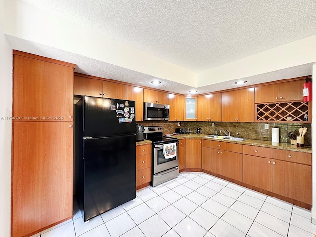 kitchen with light tile patterned flooring, appliances with stainless steel finishes, sink, and a textured ceiling