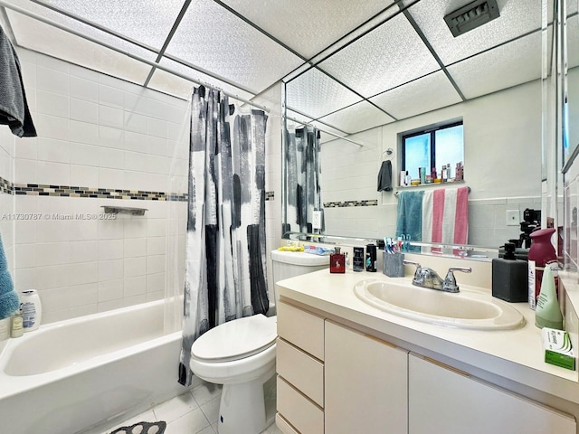 full bathroom with tile patterned flooring, vanity, toilet, a drop ceiling, and shower / bath combo with shower curtain