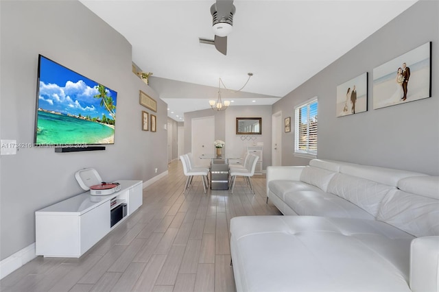 living room featuring an inviting chandelier, vaulted ceiling, and light hardwood / wood-style floors