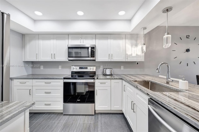 kitchen with stainless steel appliances, decorative light fixtures, sink, and white cabinets