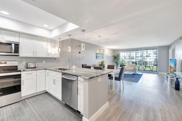 kitchen featuring sink, stainless steel appliances, kitchen peninsula, and white cabinets