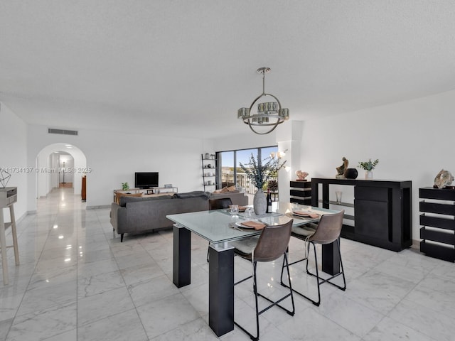 dining area featuring visible vents, an inviting chandelier, arched walkways, marble finish floor, and a textured ceiling