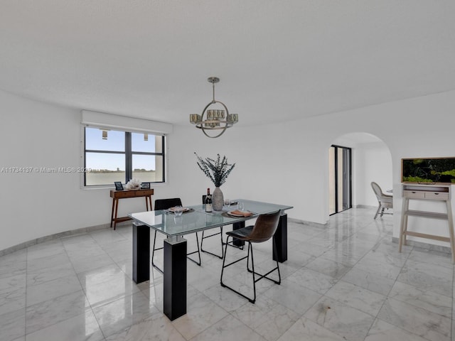 dining space with arched walkways, a chandelier, marble finish floor, and baseboards