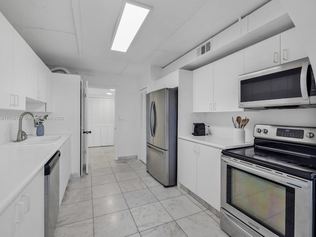 kitchen with visible vents, appliances with stainless steel finishes, white cabinetry, and a sink